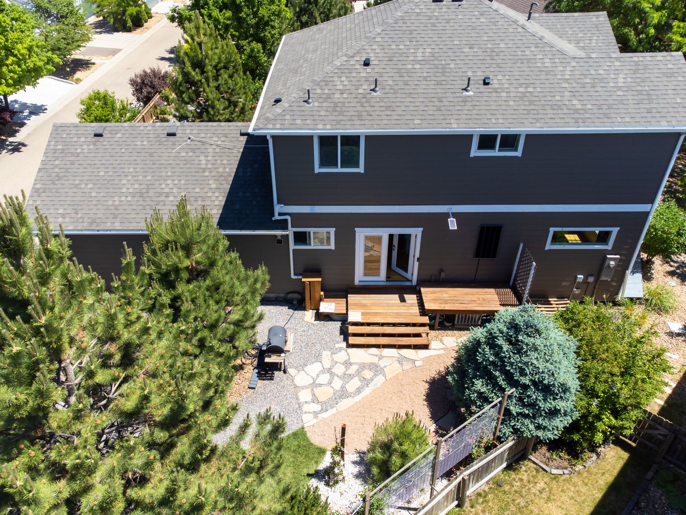 A home with a shingle roof and a stone patio, seen from above